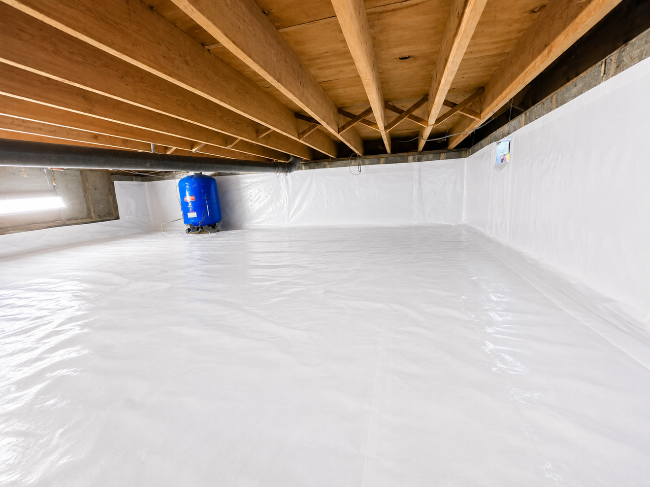 Basement foundation wall reinforced with painted white steel I-beams and white wall vapor barrier